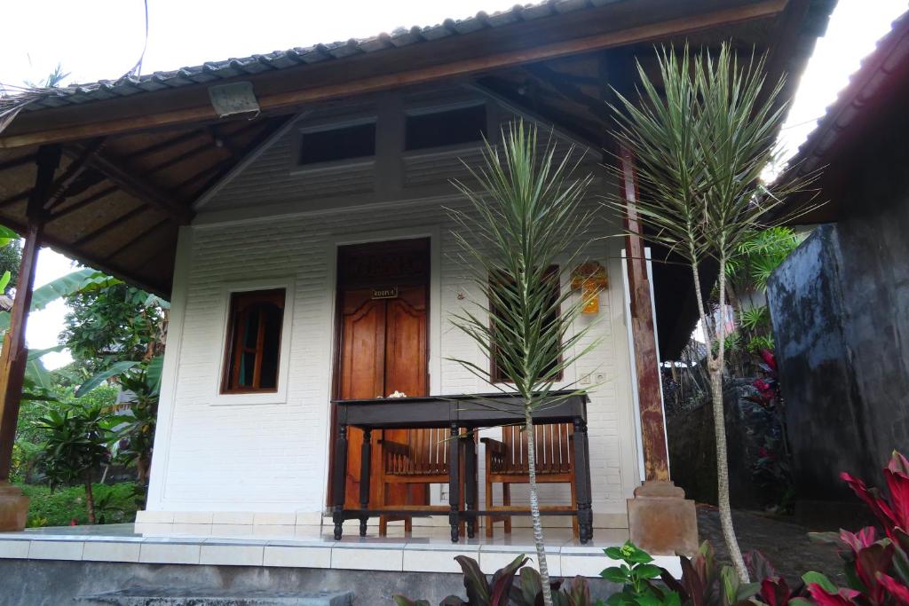 a small white house with a wooden door at Pondok Lembah Dukuh Homestay in Tirtagangga