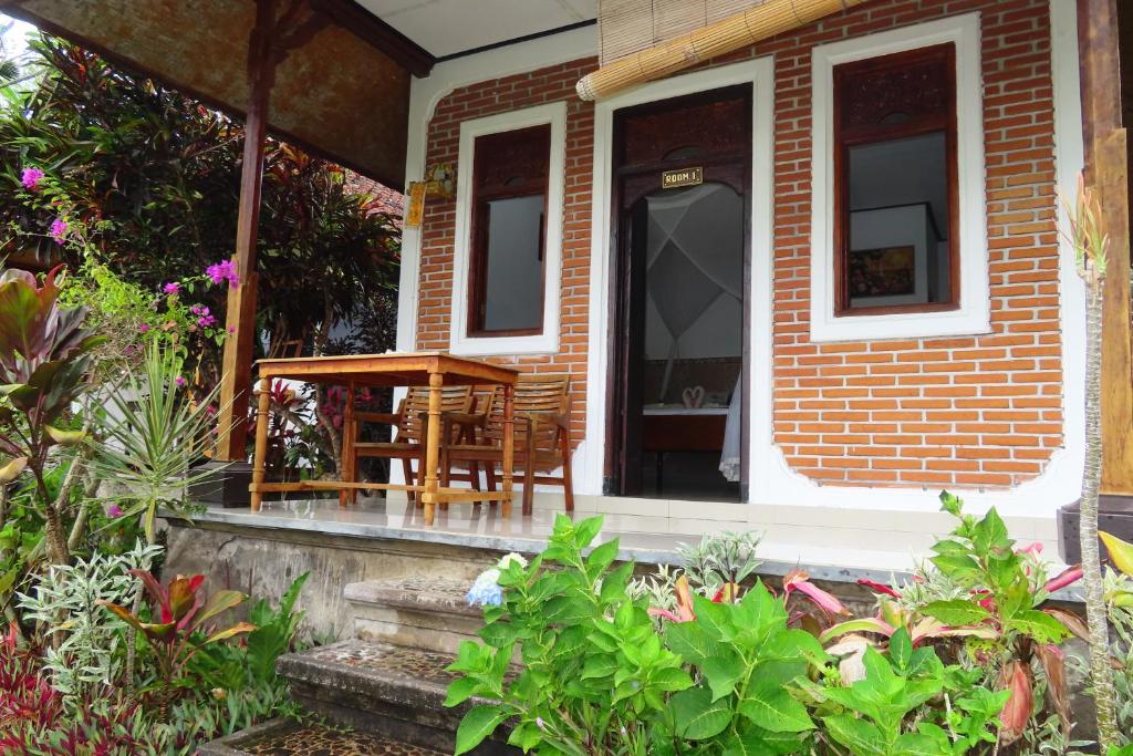 a small brick house with a table on a porch at Pondok Lembah Dukuh Homestay in Tirtagangga