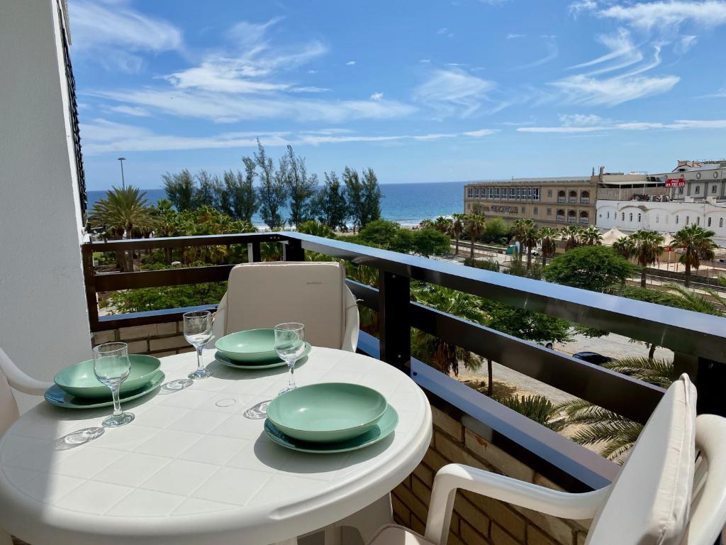 a white table and chairs on a balcony with a view of the ocean at Apartments Bambu in San Agustin