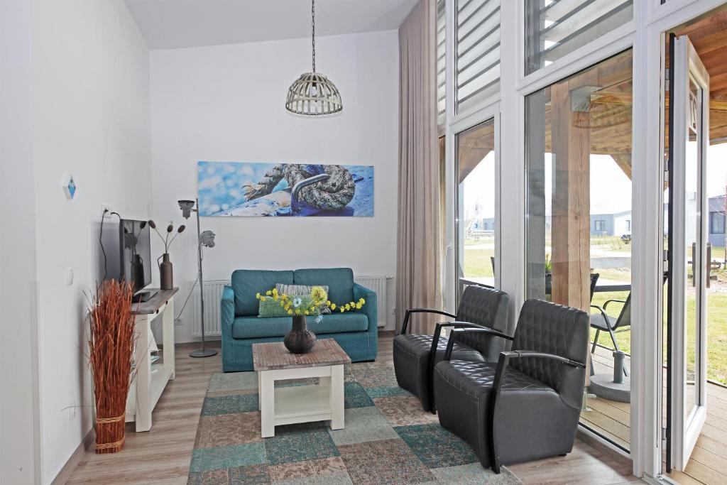 Una sala de estar con un sofá azul y sillas. en RCN Vakantiepark Bungalow de Dukdalf, en Kamperland
