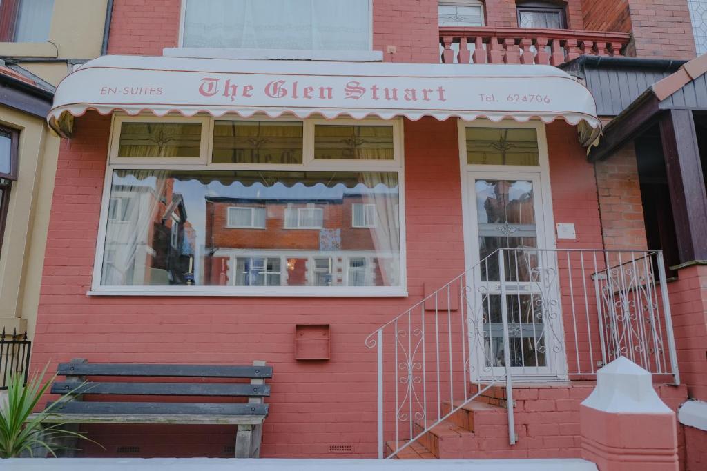 a red building with a bench in front of a window at The Glen Stuart hotel in Blackpool