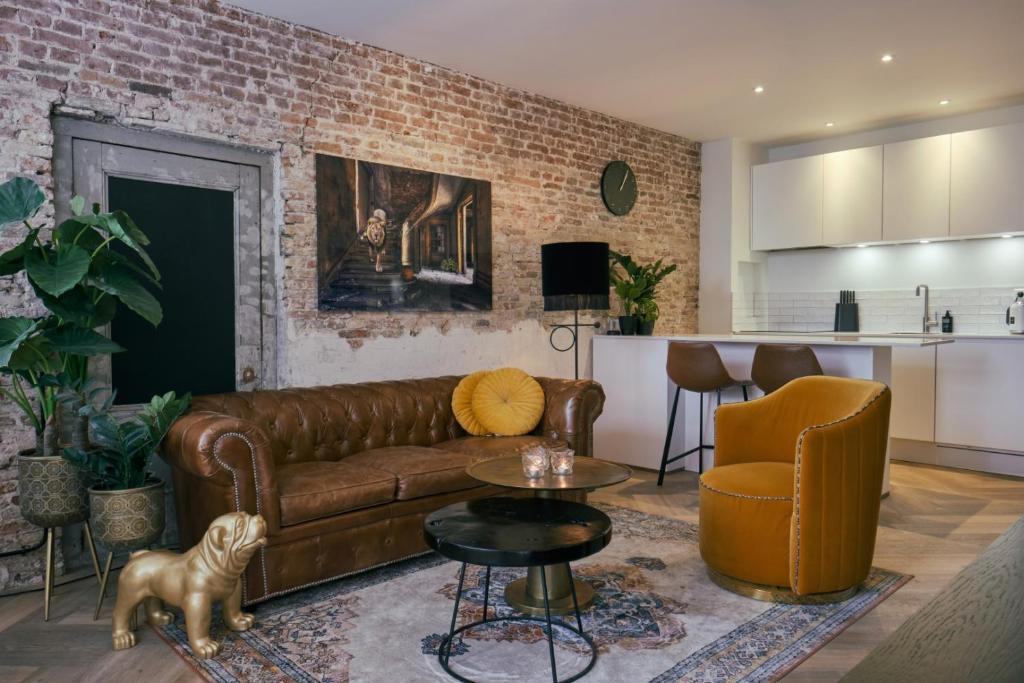a living room with a brown couch and a kitchen at RITCH Aparthotel Alkmaar in Alkmaar