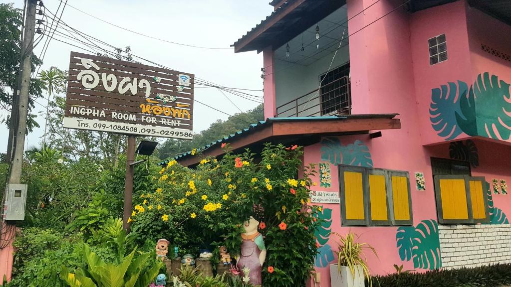 um edifício cor-de-rosa com um arbusto florido à sua frente em Ingpha Room For Rent em Satun