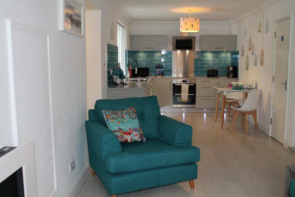 a living room with a green chair and a kitchen at BONNIE'S APARTMENT, adults only in Bowness-on-Windermere