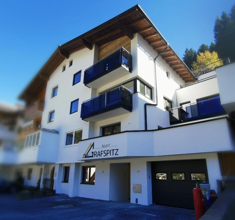 ein weißes Gebäude mit blauen Balkonen darauf in der Unterkunft Apart Grafspitz in Ischgl