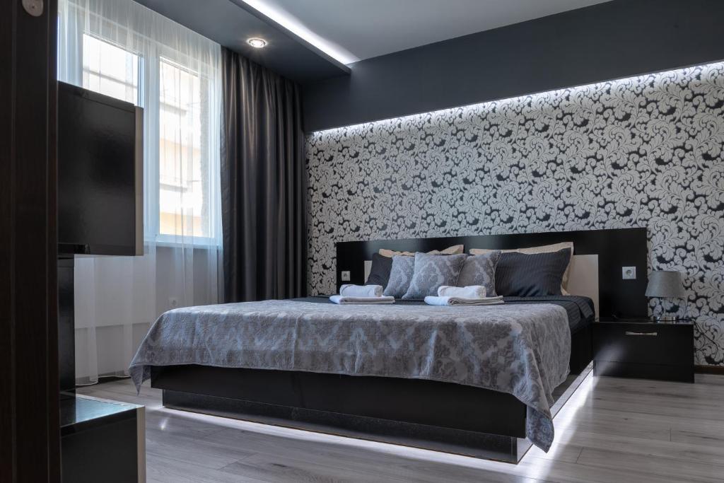 1 dormitorio con 1 cama y pared con TV en Apartment Central-LUX 1 en Veliko Tŭrnovo