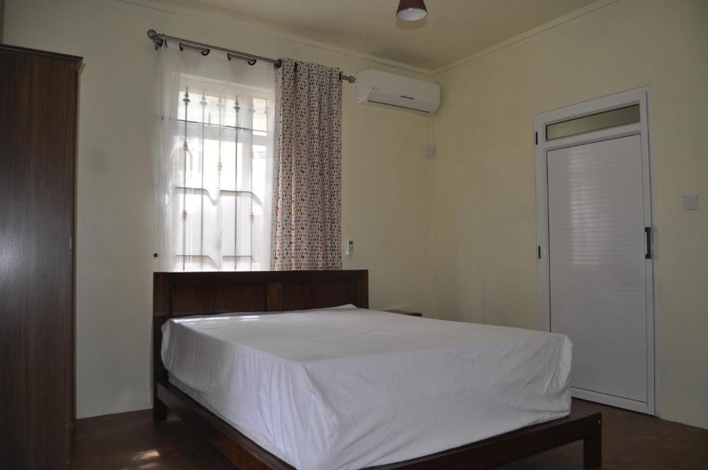una camera con un letto bianco e una finestra di Moringi (Veer Residences) a Trou d'Eau Douce