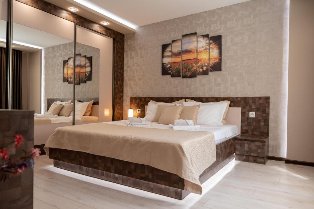 a bedroom with a large bed and two paintings on the wall at Apartment Central-LUX in Veliko Tŭrnovo