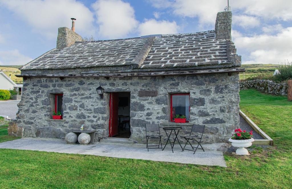 ein altes Steinhaus mit einem Tisch und Stühlen in der Unterkunft 1844 Seascape Cottage Is located on the Wild Atlantic Way in Fanore