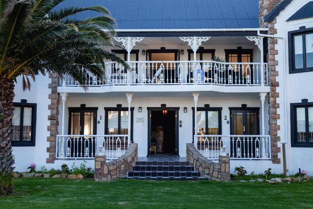 a white house with a balcony and a porch at Villa Le Roc Kleinmond Accommodation in Kleinmond