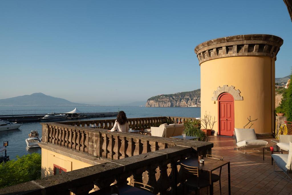 uma mulher sentada numa varanda com vista para a água em Marina Piccola 73 em Sorrento