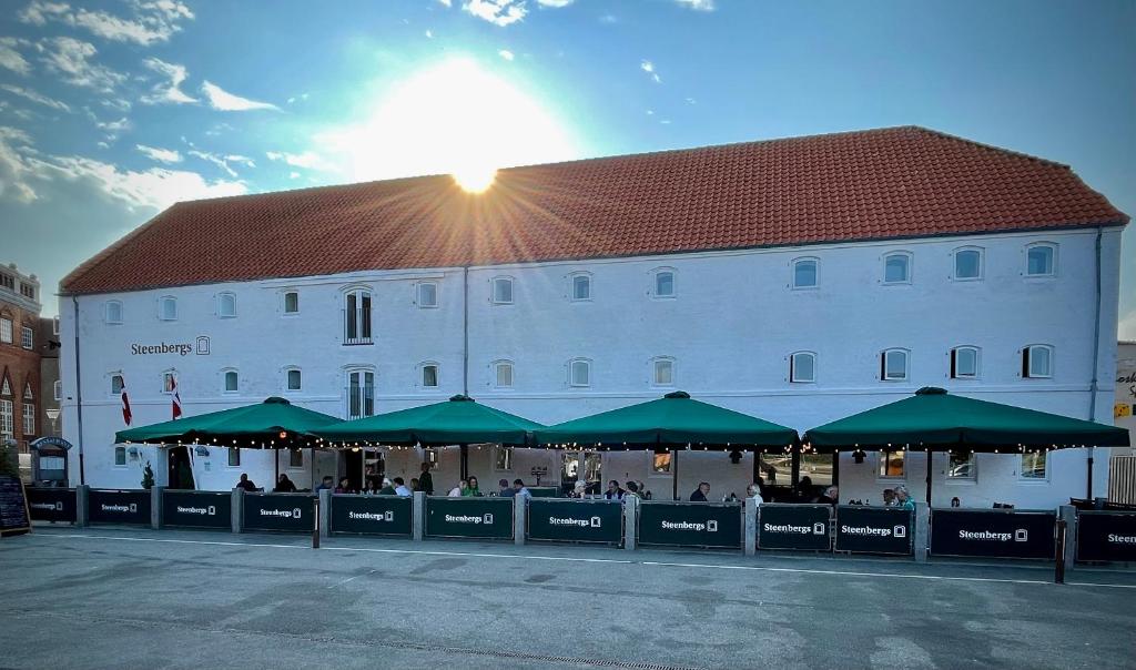 a large white building with green umbrellas in front of it at Hotel Steenbergs in Nykøbing Mors