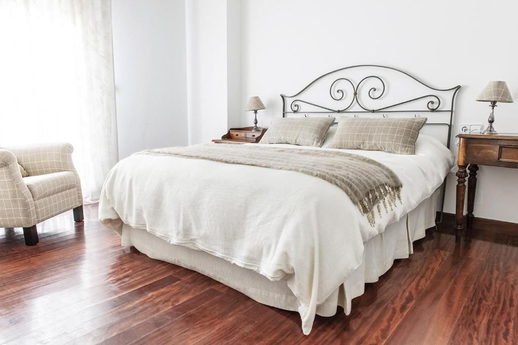 ein Schlafzimmer mit einem großen weißen Bett und einem Stuhl in der Unterkunft Apartamento Céntrico y Acogedor in Pontevedra