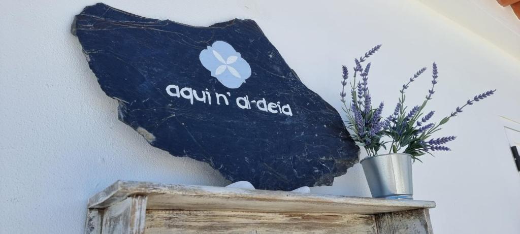 a sign on a wall with a vase of flowers at Aqui n' al-deia in Mértola