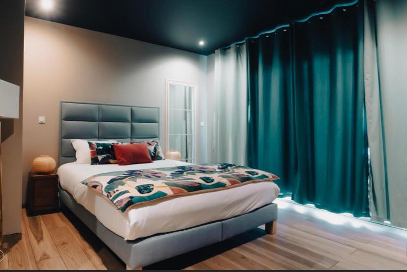 a bedroom with a large bed with blue curtains at Palm Beach in Ajaccio