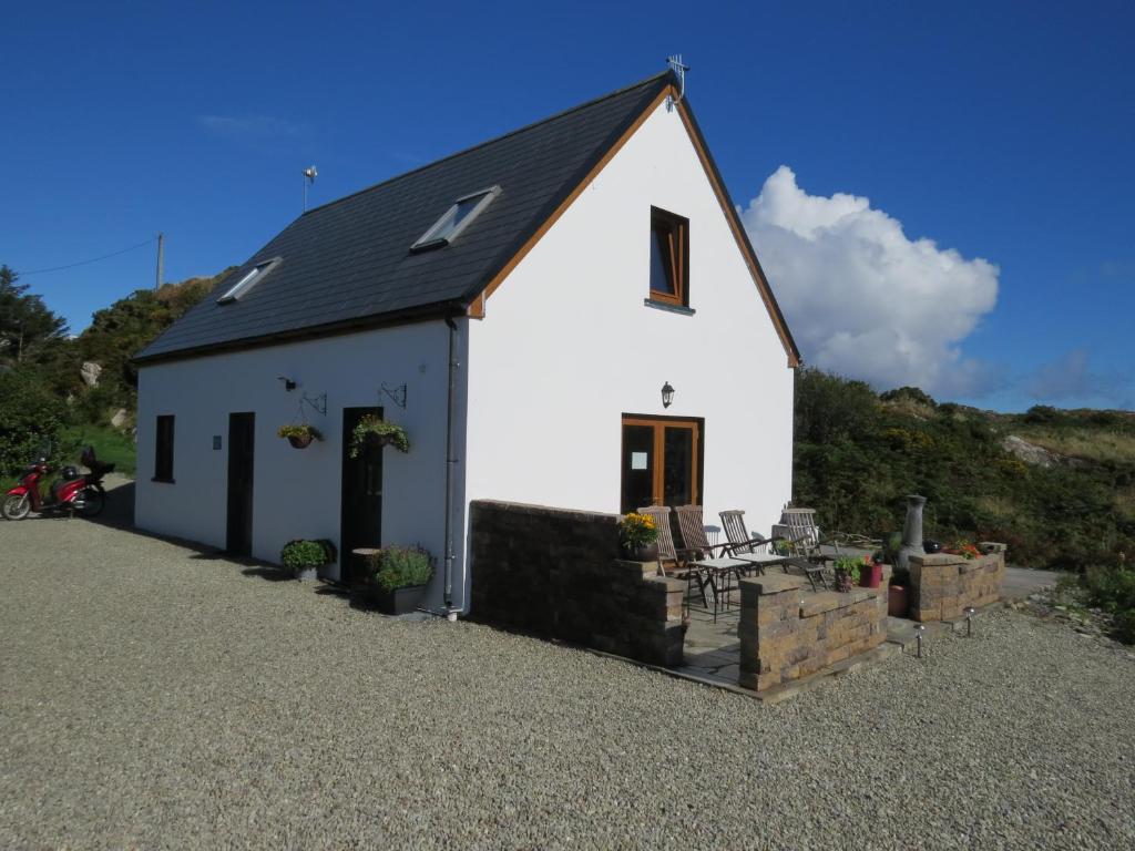 a white cottage with a black roof on a gravel driveway at Mizen View in Goleen