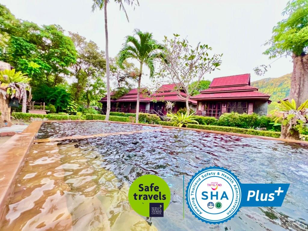une piscine en face d'une maison avec un bâtiment dans l'établissement Baan Laanta Resort & Spa - SHA PLUS, à Ko Lanta