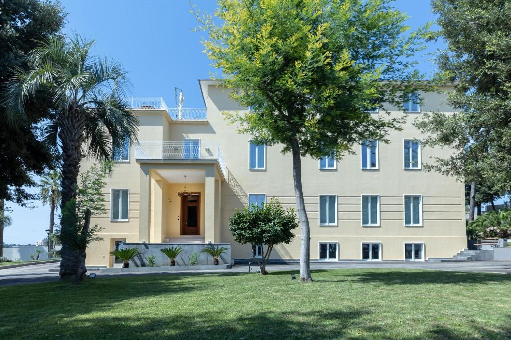 duży biały budynek z drzewami przed nim w obiekcie RIAMA AGRIRESORT w mieście Napoli