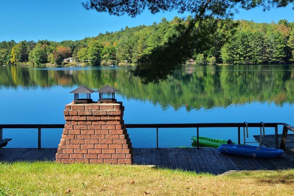 uma chaminé de tijolo sentada ao lado de um lago em Year-round Waterfront Green Cottage On Vert Lake em Val-des-Bois