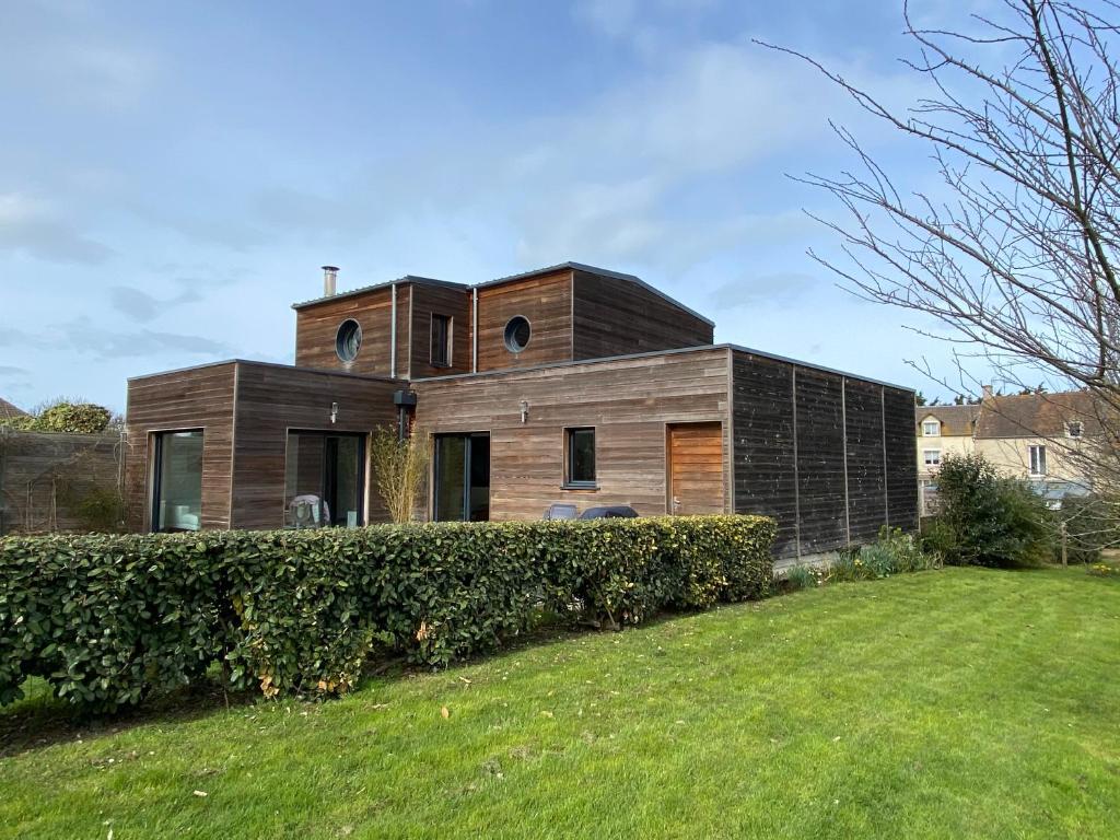 a wooden house with a green yard at Belle villa contemporaine & lumineuse plage normandie in Luc-sur-Mer