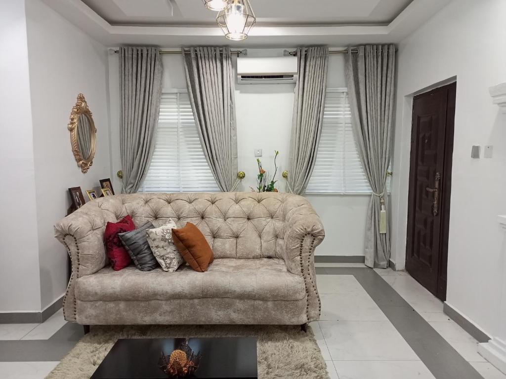 uma sala de estar com um sofá com almofadas em E - Glisters Home em Warri