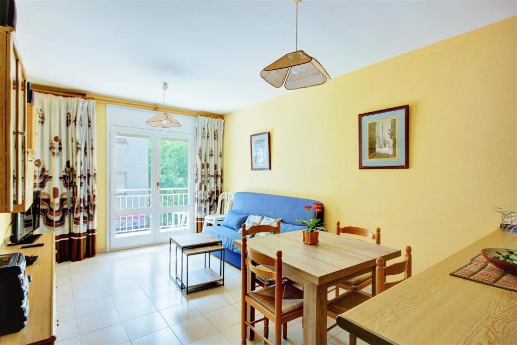 ein Wohnzimmer mit einem Tisch und einem blauen Sofa in der Unterkunft Puig Rom 115 Roses - Immo Barneda in Roses