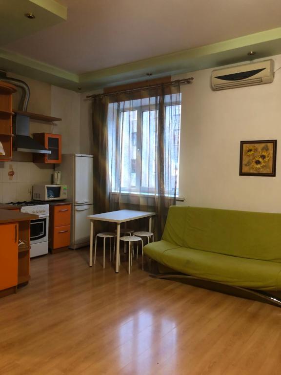 uma sala de estar com um sofá verde e uma mesa em Квартира-студия на Котляра em Kharkov