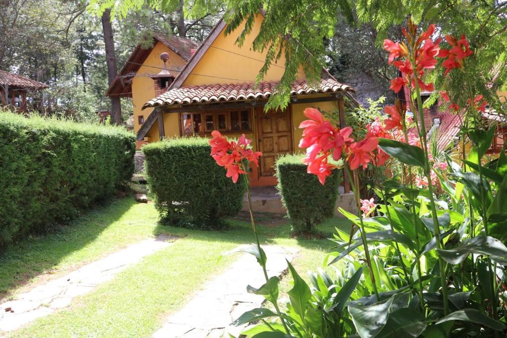 un jardín con flores rojas frente a una casa en Cabañas Lupita 22 en Mazamitla