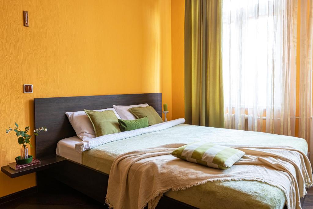 a bedroom with a bed with yellow walls and a window at Апартаменты в историческом центре на Репина, 52 in Kaliningrad