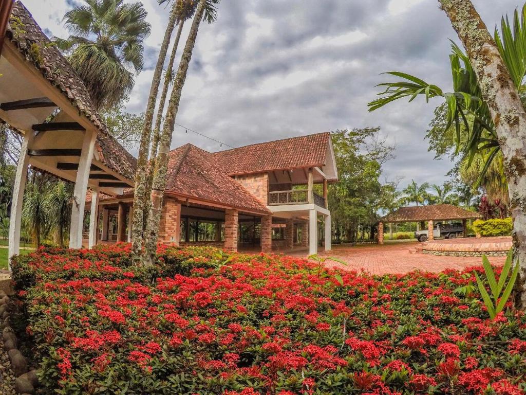 una casa con flores rojas delante de ella en Hotel Hacienda Gualanday, en Villavicencio