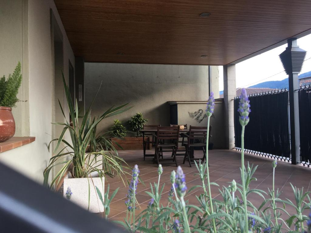 a patio with a table and chairs and purple flowers at Can Musiquem amb Piscina in Les Planes d'Hostoles