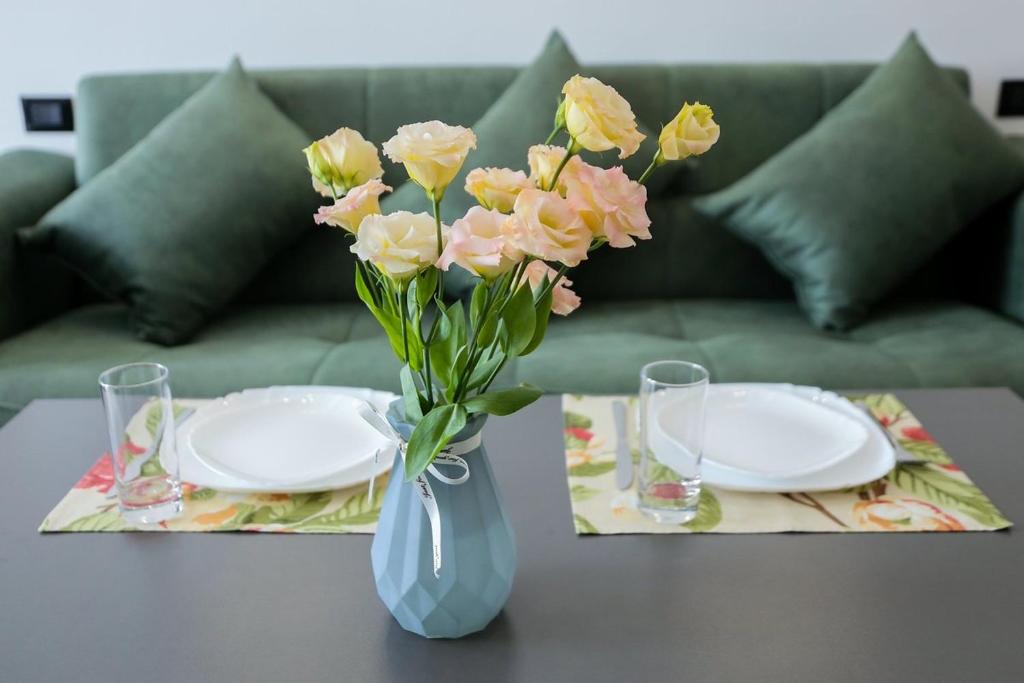 um vaso de flores sentado numa mesa com dois pratos em Апарт-отель Nine Rooms em Yerevan
