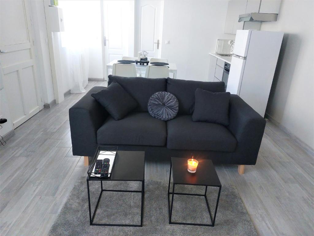 sala de estar con sofá negro y 2 mesas en Charmante maison cosy T2 avec terrasse en Tremblay En France