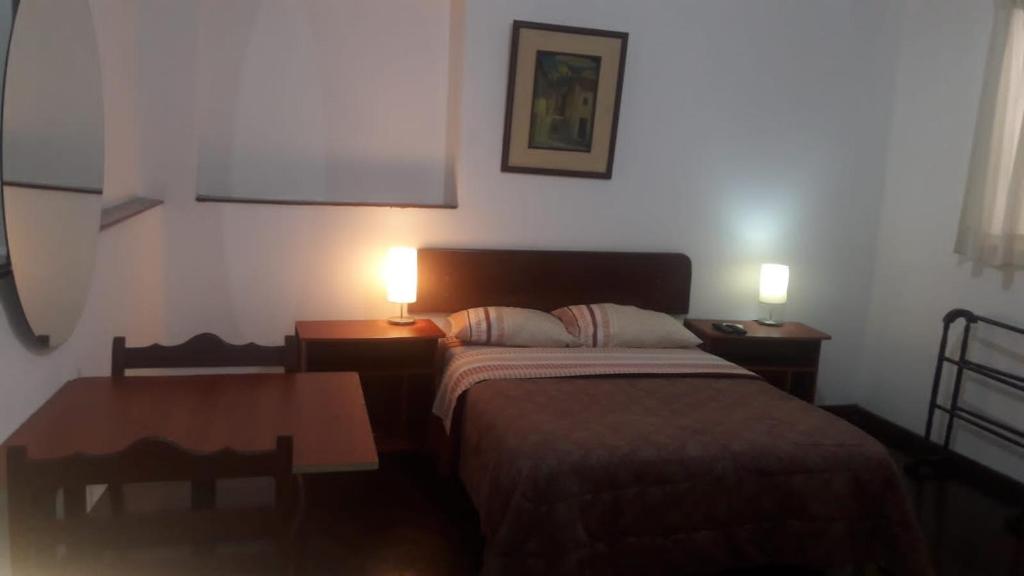 a bedroom with a bed and a table and two lamps at Hospedaje Schell in Lima
