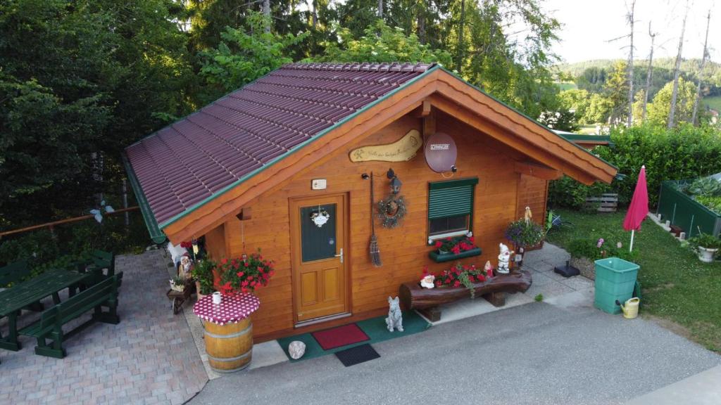 een klein houten huis met een bank in een tuin bij Ferienhaus Barbara in Ebenthal