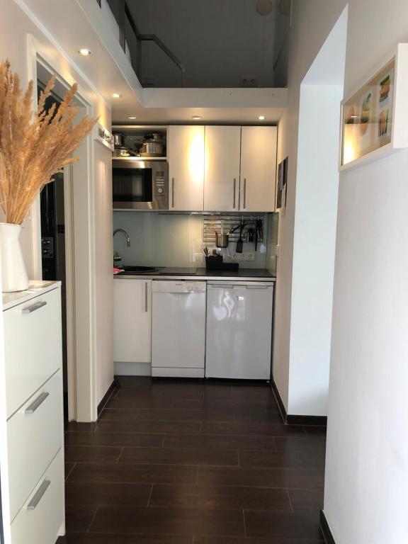 a kitchen with white cabinets and a wooden floor at Apartment TinyHouse mit Pool, Outdoor Whirlpool und Garten in Petershagen