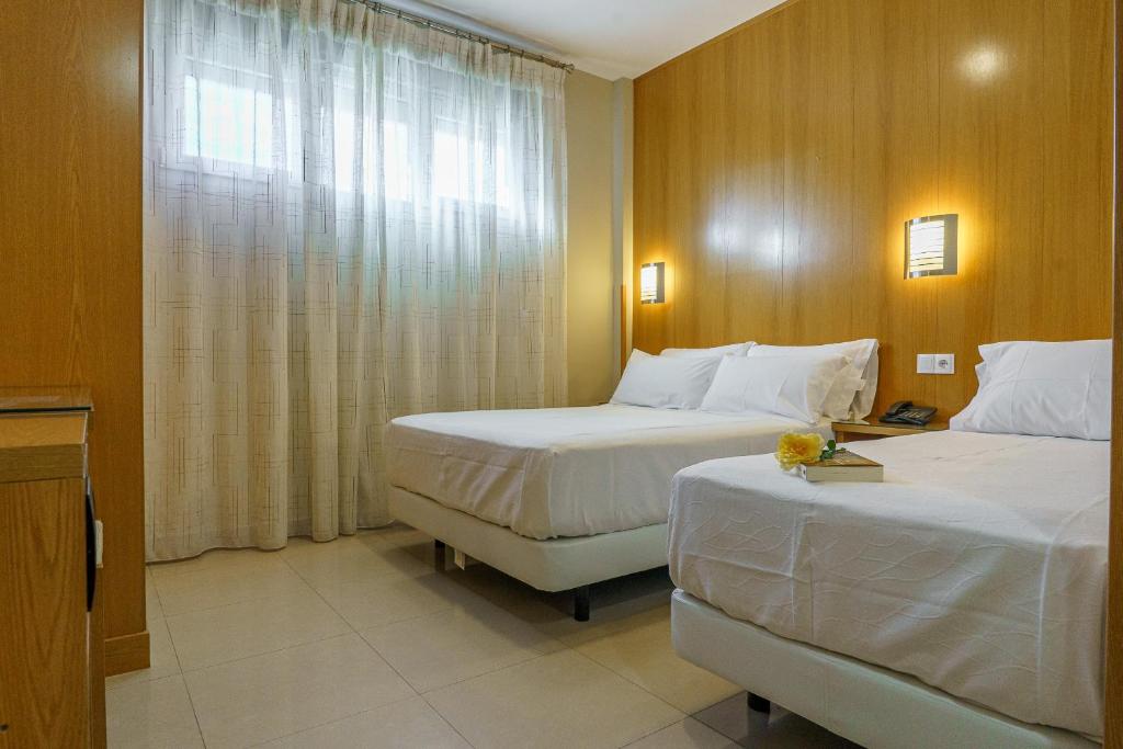 a hotel room with two beds and a window at Hostal Acueducto Los Milagros in Mérida
