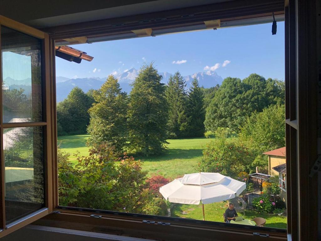 a window with a view of a yard with an umbrella at Chalet Dahoam in Garmisch-Partenkirchen