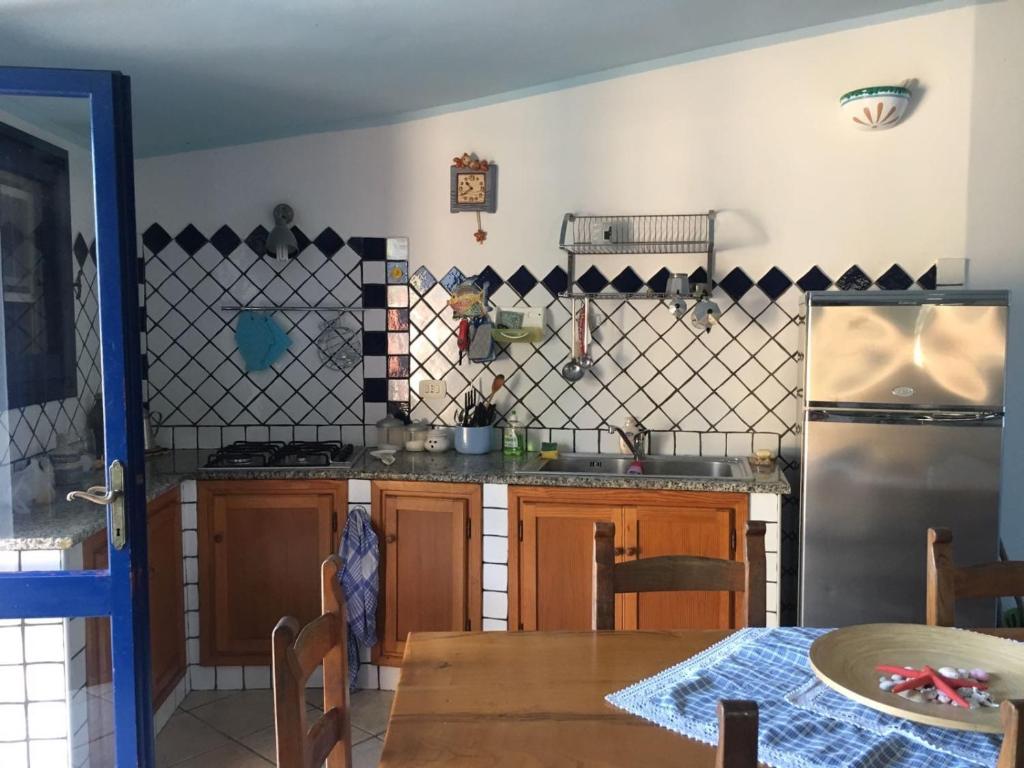 a kitchen with a table and a refrigerator at Villa Vera trifamigliare con ingresso diretto 20 mt al mare clima wi-fi bbq in Cala Liberotto