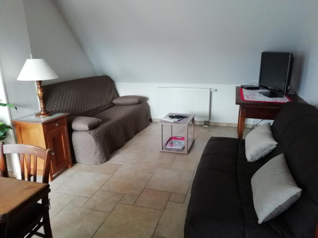 ein Wohnzimmer mit einem Sofa und einem Tisch in der Unterkunft Gîte HAURY in Cleebourg