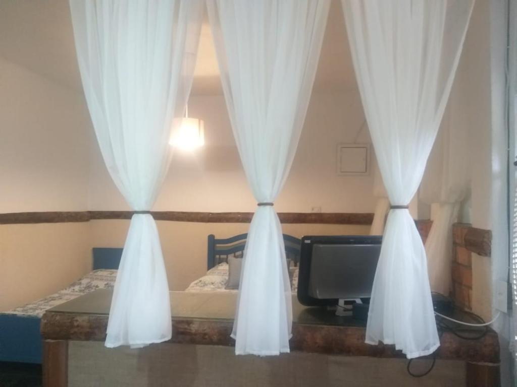 um quarto com uma cama com cortinas e uma televisão em Chalé do lago Ladeira de Pedra em Salesópolis
