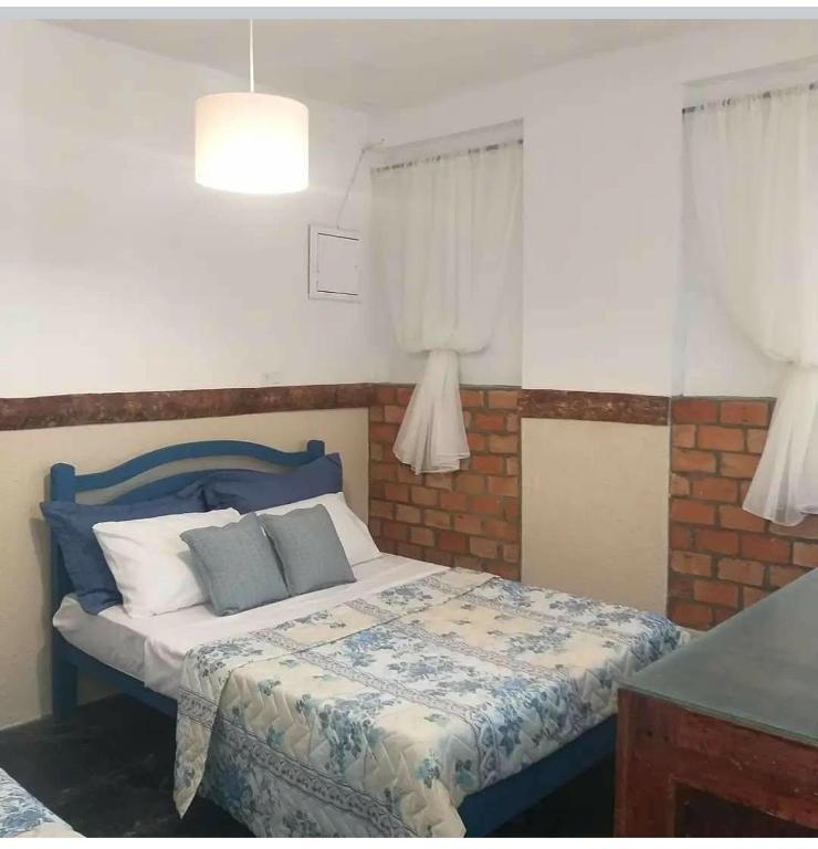 a bedroom with a bed with a blue headboard and pillows at Chalé do lago Ladeira de Pedra in Salesópolis