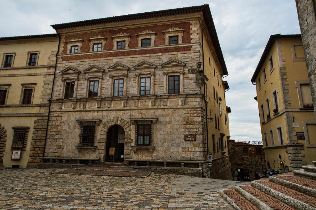 um antigo edifício de tijolos numa rua de calçada em Contucci Residenze d'Epoca em Montepulciano