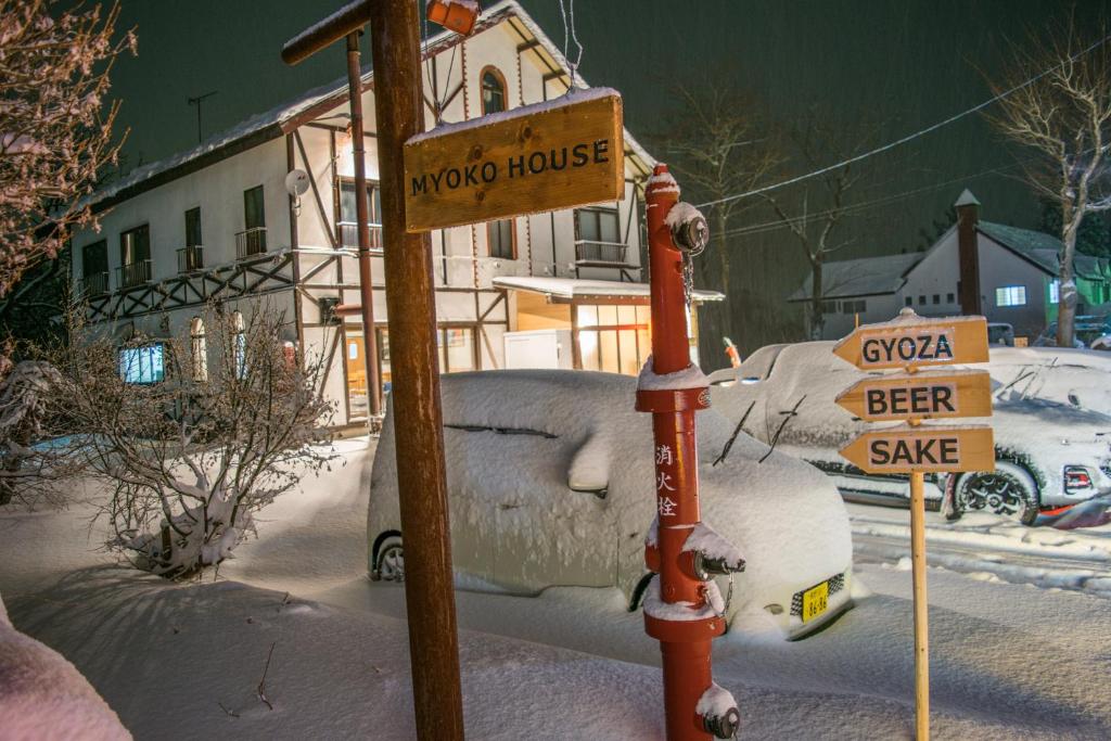 a street sign in the snow next to a house at Myoko House in Myoko
