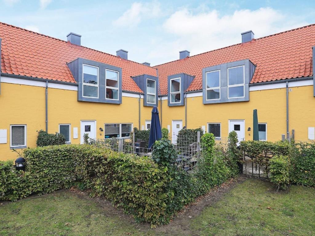 une maison jaune avec une haie devant elle dans l'établissement 6 person holiday home in Skagen, à Skagen