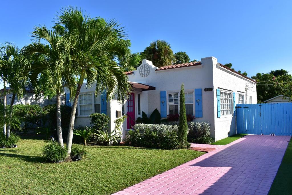 a white house with palm trees in a yard at In the heart of West Palm Beach, pets welcome in West Palm Beach