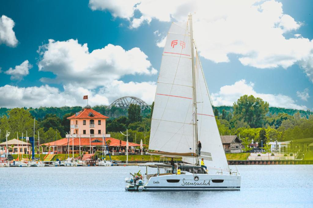 a sailboat on the water in front of a harbor at Seensuchtsresort in Bitterfeld