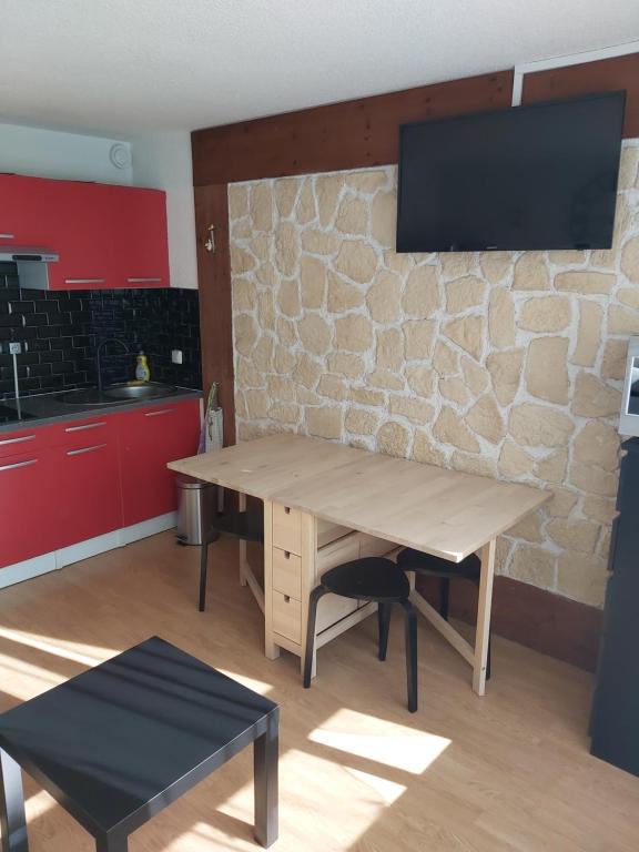 uma cozinha com uma mesa de madeira e uma televisão numa parede de pedra em STUDIO 20m2 em Puy-Saint-Vincent
