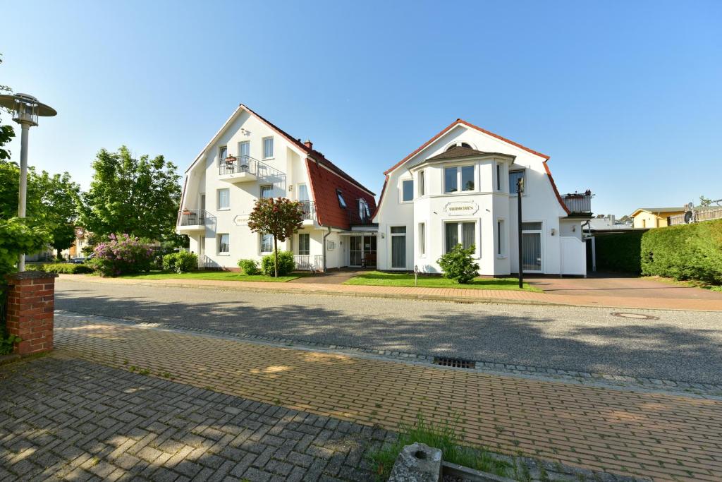 two houses on a street with a cobblestone road at Pension Heimchen in Bansin