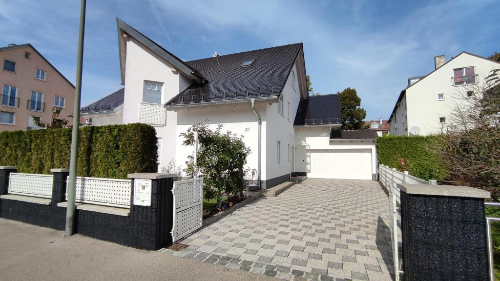 a white house with a fence and a driveway at Ferienwohnung Krause in Augsburg